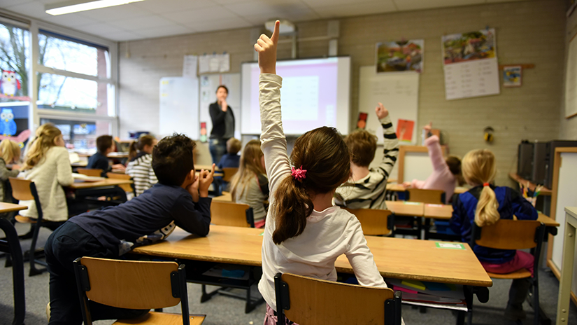 Klas met kinderen waarbij één haar vinger opsteekt